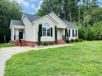 Charming single story home with white siding, a well-manicured lawn, and a brick lined walkway at 105 Watson Cir, Clayton, NC 27527