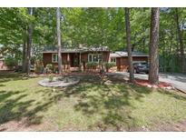 Charming, one-story home with wooded front yard, brown siding, and an American flag at 1801 Irish Blvd, Sanford, NC 27332