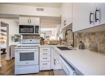 Bright kitchen features white cabinets, modern appliances, tile backsplash, and wood flooring at 220 Elizabeth St # F-2, Chapel Hill, NC 27514