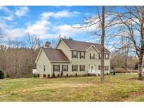 Charming two-story home features a well-manicured lawn and classic architecture under a bright, partly cloudy sky at 250 Spring View Ln, Pittsboro, NC 27312