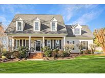 Charming traditional home with manicured lawn, dormer windows, brick steps, and a welcoming front porch at 4704 Homeplace Dr, Apex, NC 27539