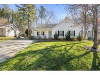 Charming single-story home with a welcoming front porch, lush lawn, and mature trees at 513 Jaffiley Ct, Wake Forest, NC 27587