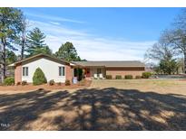 Charming single-story home with a brick facade, manicured lawn, and a bright red front door at 7516 Mourning Dove Dr, Sanford, NC 27332