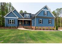 Charming blue home with manicured lawn, brick base, craftsman accents, and inviting covered entryway at 110 Purslane Dr, Franklinton, NC 27525