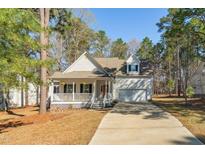Charming home featuring a welcoming front porch, green shrubbery, and an attached two car garage at 138 Sherwood Ln, Sanford, NC 27332
