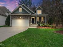 Charming home with stone accents, manicured lawn and inviting curb appeal at twilight at 1428 Heritage Links Dr, Wake Forest, NC 27587