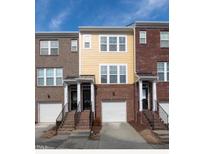 Charming townhome showcasing a brick facade, covered entrance, and attached garage, perfect for modern living at 317 Michigan Ave, Cary, NC 27519