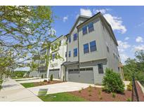 New gray and white townhome featuring a two-car garage, modern design, and professional landscaping at 4706 Cypress Tree Ln, Raleigh, NC 27612