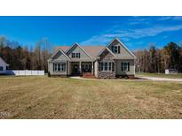 Charming exterior view of a two-story home with stone accents and a well-manicured lawn under a clear sky at 6720 Colleen Rd, Rocky Mount, NC 27803