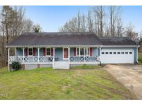 Charming single-story home with a covered porch, red shutters, attached garage, and well-maintained front lawn at 752 S Ridge Rd, Burlington, NC 27217