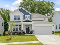 Charming two-story home with a two-car garage, landscaped yard, and blue accents at 789 Old Station Pointe, Angier, NC 27501