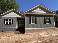 New construction home featuring gray siding, brick foundation, black shutters, and a covered front entryway at 977 Lewis Rd, Zebulon, NC 27597