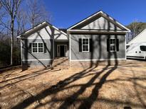 Charming new construction home featuring gray siding, black shutters, and brick accents under a brilliant blue sky at 977 Lewis Rd, Zebulon, NC 27597
