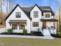 Charming two-story farmhouse-style home with black framed windows, a covered porch, and beautifully landscaped front yard at 110 Black Swan Dr, Youngsville, NC 27596