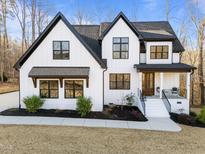 Stunning new construction farmhouse with modern black accents, manicured landscaping, and inviting front porch at 110 Black Swan Dr, Youngsville, NC 27596