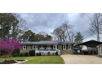 Charming single-story home featuring a cozy front porch, lush landscaping, and metal roof at 1209 Mill Valley Rd, Fuquay Varina, NC 27526