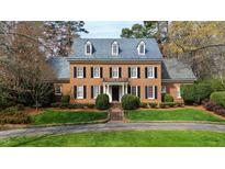 Charming two-story brick home with black shutters, dormer windows, manicured lawn and mature landscaping at 2405 Coley Forest Pl, Raleigh, NC 27612