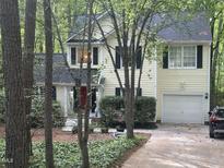 Charming two-story home with yellow siding, black shutters, and a red front door, nestled among mature trees at 27 Creeks Edge Ct, Durham, NC 27713