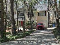 Charming two-story home with a red door, black shutters, and an inviting driveway, nestled amongst mature trees at 27 Creeks Edge Ct, Durham, NC 27713