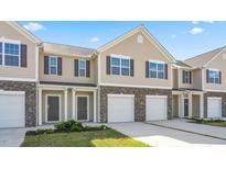Two-story townhome exterior with stone accents, a garage, and a well-manicured lawn under a bright blue sky at 2838 Egert Dr, Haw River, NC 27258