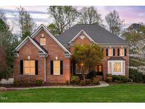 Charming brick home featuring a manicured lawn, flowering trees, and classic architectural details at 4009 Summer Brook Dr, Apex, NC 27539