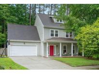 Charming two-story home featuring a red front door, covered porch, attached garage and landscaped yard at 4070 Landover Ln, Raleigh, NC 27616