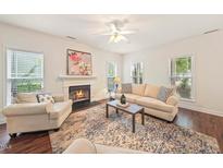 Bright living room featuring a fireplace, neutral-toned sofa and armchair, and a decorative rug at 4070 Landover Ln, Raleigh, NC 27616