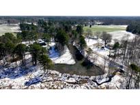 Scenic aerial view featuring a pond, trees, and fields covered in a layer of snow at 6509 Fowler Rd, Zebulon, NC 27597