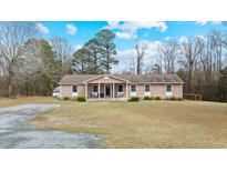 Charming single-story home featuring a welcoming front porch with rocking chairs and a well-maintained lawn at 7155 Old Fairground Rd, Benson, NC 27504