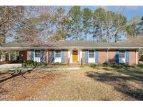 Charming brick home with blue shutters, a yellow door, and mature trees in a well-maintained yard at 914 S Crescent Dr, Smithfield, NC 27577
