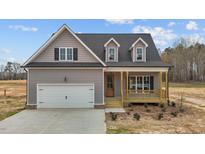 Charming home with gray siding, covered porch, dormers and a white garage door enhancing its curb appeal at 9353 Turkey Way, Middlesex, NC 27557