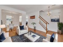 Bright living room with hardwood floors, white furniture, and a view of the dining area at 10707 Edmundson Ave, Raleigh, NC 27614