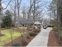 Charming brick home with a long driveway, mature trees, and an American flag displayed at 11912 Appaloosa E, Raleigh, NC 27613
