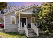 Charming home featuring light gray siding, white trim, and a welcoming front porch with steps and chair at 1614 Homewood Ave, Durham, NC 27707