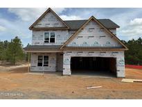 New construction home featuring a two-car garage with the exterior still in progress under a cloudy blue sky at 200 Dove Rd, Cameron, NC 28326