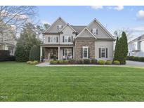Charming two-story home featuring stone accents, a covered porch, and a lush green lawn at 209 Morning Oaks Dr, Holly Springs, NC 27540