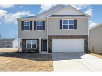 Two story home featuring a two-car garage, stone accents, neutral siding and manicured landscaping at 2902 Cullens Dr, Graham, NC 27253
