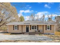 Charming home features tan siding, shutters, a covered front porch and well maintained landscaping at 2914 Old Stage N Rd, Coats, NC 27521