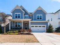 Charming two-story home with blue siding, a well-manicured lawn, and an attached two-car garage at 521 Ivy Arbor Way, Holly Springs, NC 27540