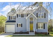 Charming two-story home with a welcoming yellow door and an attached garage on a sunny day at 5412 Pennfine Dr, Raleigh, NC 27610