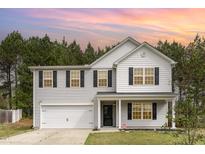 Charming two-story home features a two-car garage and classic black shutters set against a backdrop of lush, mature trees at 709 Conifer Ct, Creedmoor, NC 27522