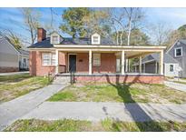 Charming red brick home featuring a covered front porch,dormers, and a well-maintained front yard at 818 Eastern Ave, Rocky Mount, NC 27801