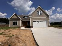 Charming single-Gathering home featuring vertical siding, a two-car garage, and a concrete driveway under a bright, partly cloudy sky at 141 Noramac Ct, Selma, NC 27576