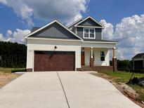 Two-story home featuring a stained garage door, light siding, and craftsman columns at 163 Noramac Ct, Selma, NC 27576