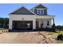 Charming new construction home with a two car garage, a mix of siding colors, and an unfinished front yard at 163 Noramac Ct, Selma, NC 27576