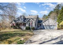 Charming gray home featuring red shutters, a covered porch, a two-car garage, and a manicured front lawn at 212 Wintergreen Dr, Garner, NC 27529