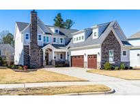 Charming two-story home with stone accents, three-car garage, well-manicured lawn, and a welcoming covered front porch at 3847 Stoneridge Forest Dr, Raleigh, NC 27612