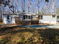 Charming single-story home featuring a wood deck and mature trees surrounding the property at 471 Deer Run, Pittsboro, NC 27312