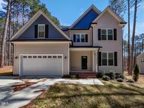 Charming two-story home featuring a manicured lawn, attached two-car garage, and eye-catching blue and tan color scheme at 6233 Reagan Ln, Wake Forest, NC 27587