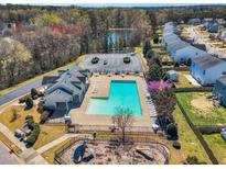 Aerial view of community pool, playground, parking, pond, and clubhouse, surrounded by homes and trees at 6817 Osprey Landing Dr, Wendell, NC 27591